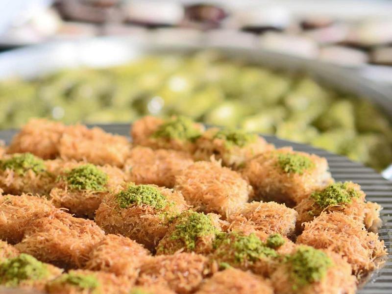 Runde, braune Kekse mit grünen Pistazienstücken auf einem Metallgitter, unscharfer Hintergrund.