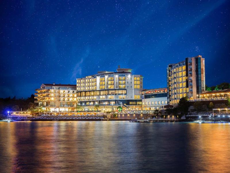 Modernes Hotel am Wasser mit leuchtenden Fenstern und Sternenhimmel bei Nacht.