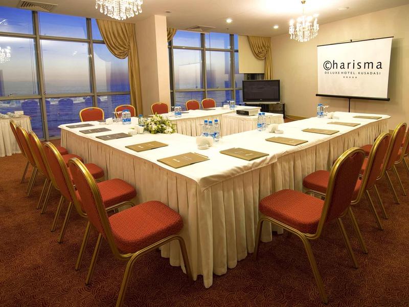 Einrichtung mit U-förmigem Tisch, rot gepolsterten Stühlen und Blick auf Stadt bei Dämmerung.