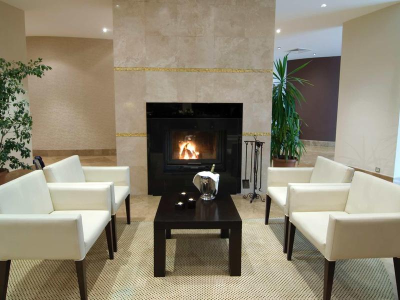 Gemütlicher Sitzbereich mit weißen Sesseln, schwarzem Tisch und Kamin in modernem Raum.