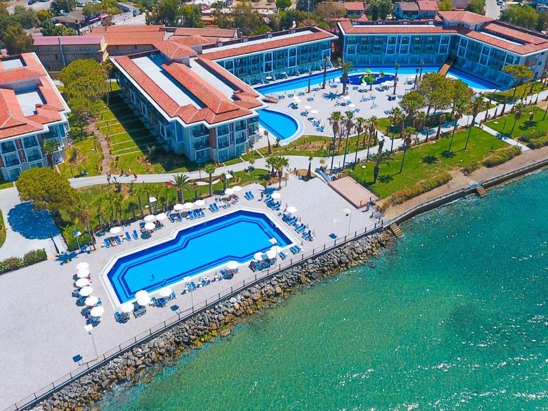 Luxusresort mit blauen Pools, roten Dächern und klarem Meerwasser an der Küste.