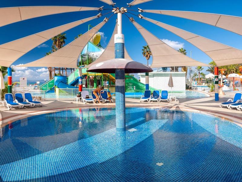 Runder Pool mit blauer Mosaikfliesen, Sonnensegel, Liegestühle und Wasserspiel im Freibad.