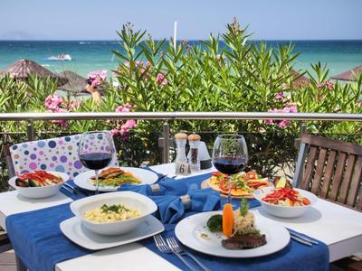 Terrazza con tavolo apparecchiato, piatti mediterranei, vino e vista sul mare