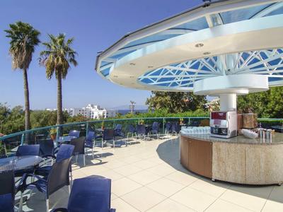 Außergewöhnliche Dachterrasse mit blauen Stühlen, Palmen und modernem runden Barbereich.