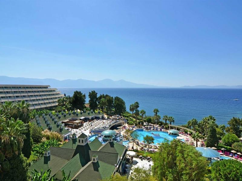 Hotelanlage mit großem Pool, Palmen und Blick auf das blaue Meer unter klarem Himmel.