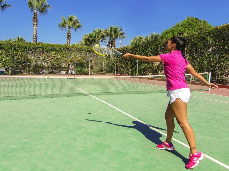 Eine Frau in Pink läuft auf einem Tennisplatz mit grünem Boden und weißen Linien.