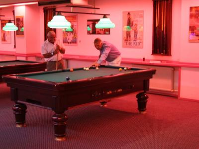 Modern hotelzwembad met glijbaan, parasols en ligstoelen buiten onder een heldere hemel.