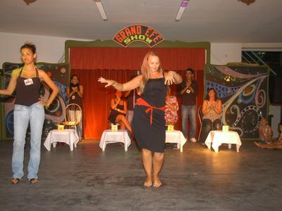 Twee vrouwen dansen op een podium met een kleurrijke achtergrond in een evenementenruimte.