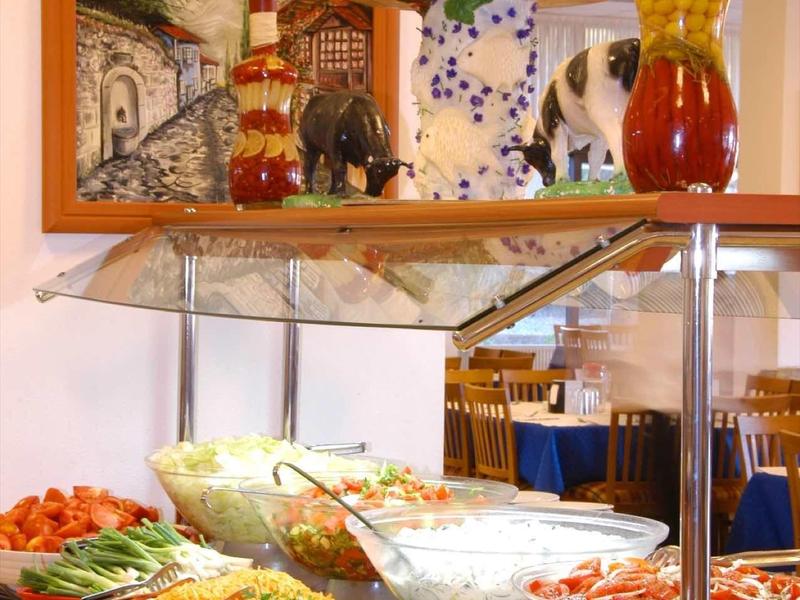 Buffet mit Salaten, Gurken, Tomaten und anderen frischen Gemüsesorten in weißen Schalen.