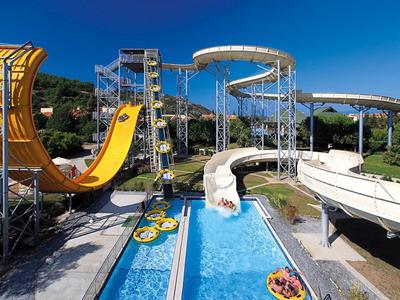 Wasserpark mit großen Rutschen, blauen Pools und bunten aufblasbaren Reifen unter klarem Himmel.