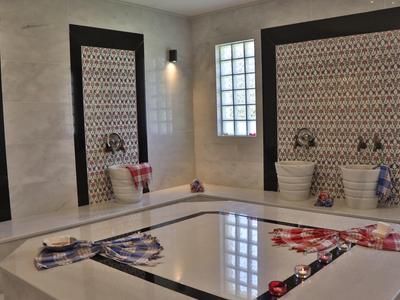 Modernes türkisches Hamam mit großen Marmorflächen und bunten dekorativen Details an den Wänden.