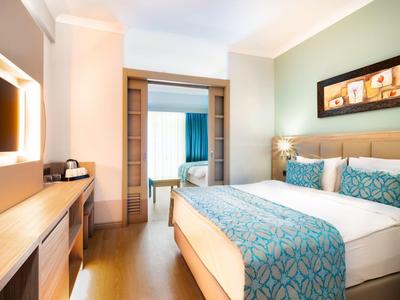 Helles Hotelzimmer mit großem Bett, blau-weißem Bettwäsche-Set und Holzmöbeln an der Wand.