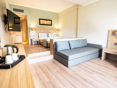 Moderner, heller Wohnraum mit grauer Couch, Holzmöbeln und Parkettboden. Fenster links.