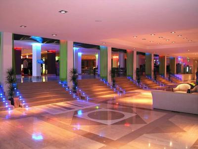 Heller Raum mit großen Fenstern, Treppen mit blauen Lichtern und moderner, beiger Sofalandschaft.