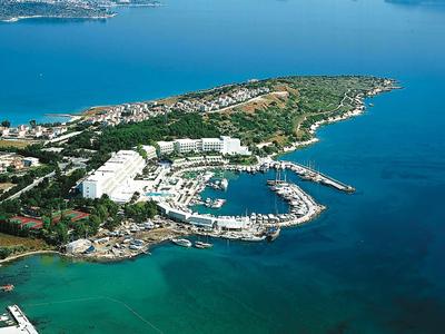 Insel mit Yachthafen, weißen Gebäuden und umgeben von klarem, blauem Meerwasser.
