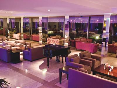 Großer, moderner Lounge-Bereich mit Sofas, Sesseln und einem schwarzen Flügelklavier bei Nacht.