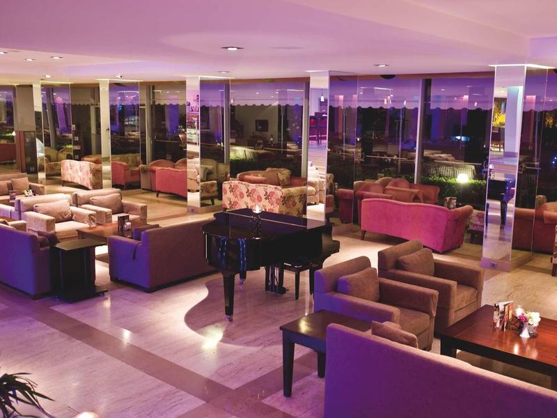 Großer, moderner Lounge-Bereich mit Sofas, Sesseln und einem schwarzen Flügelklavier bei Nacht.