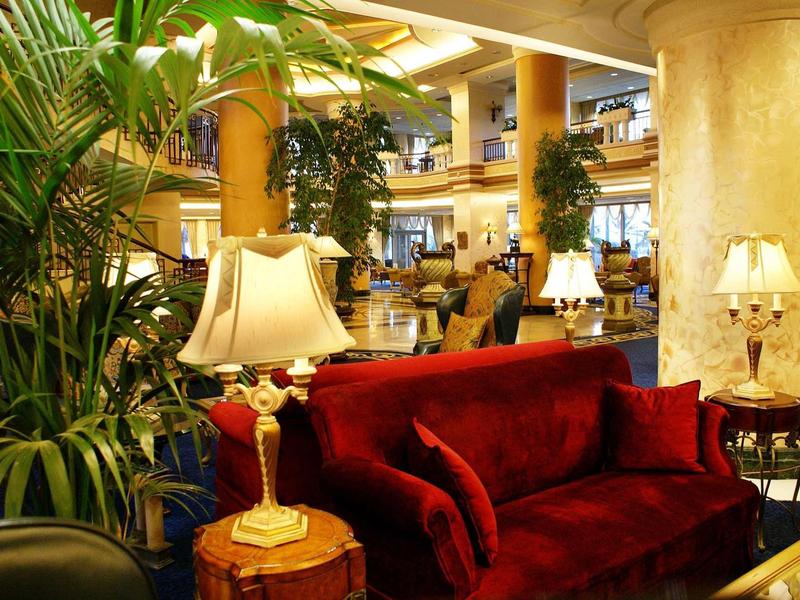 Luxuriöser Innenraum mit rotem Samtsofa, warmen Lampen und grünen Pflanzen.