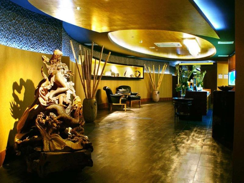 Eleganter Hotel-Flur mit warmem Licht, Holzskulptur und modernen Möbeln in Gelb- und Brauntönen.