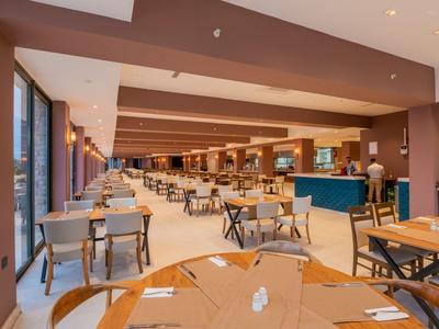 Moderner Hotellobbybereich mit Tischen, Stühlen und Theke in warmen Farben.