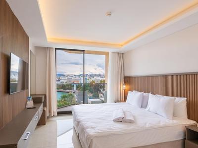Helles Hotelzimmer mit großem Bett, Wand-TV und Balkon mit Stadtblick.