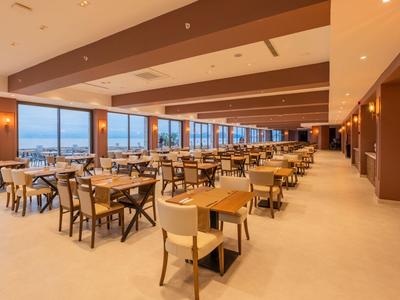 Großer, moderner Speisesaal mit Stühlen und Tischen, großen Fenstern und Blick nach draußen.