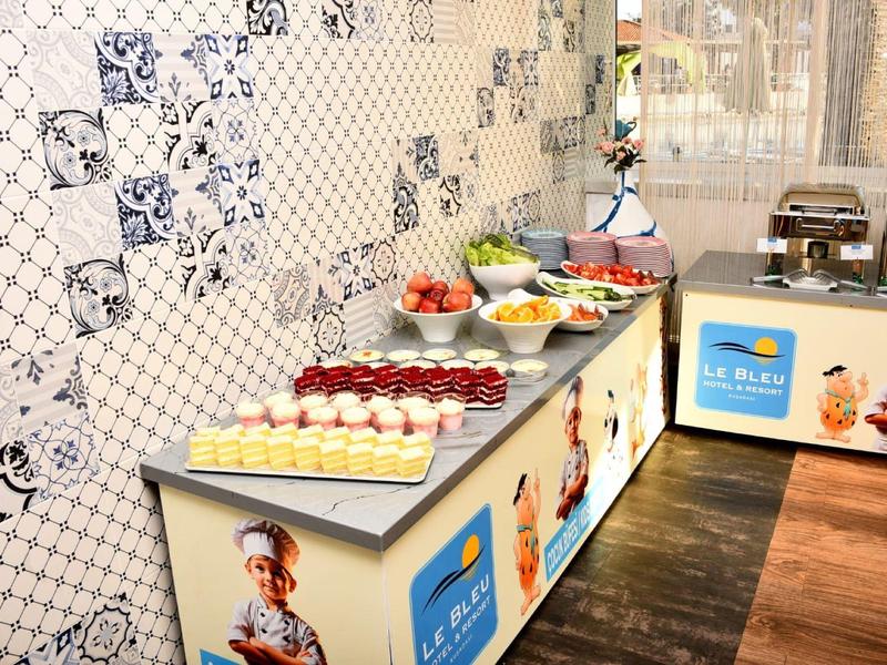 Buffet mit verschiedenen kalten und warmen Speisen in modernem Raum mit gemusterter Wand.