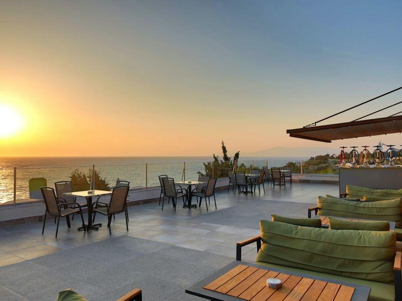Sunset over a terrace with seating and ocean views at a hotel or resort.