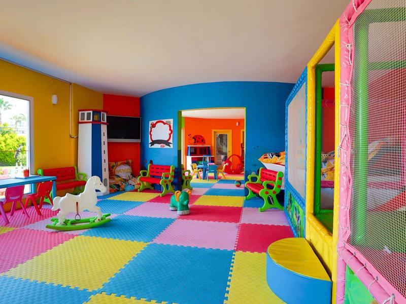 Colorful playroom with padded floor mats, toys, and large windows, designed for children's activities.