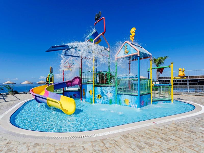 Colorful water playground with slides and splash features under a clear blue sky.
