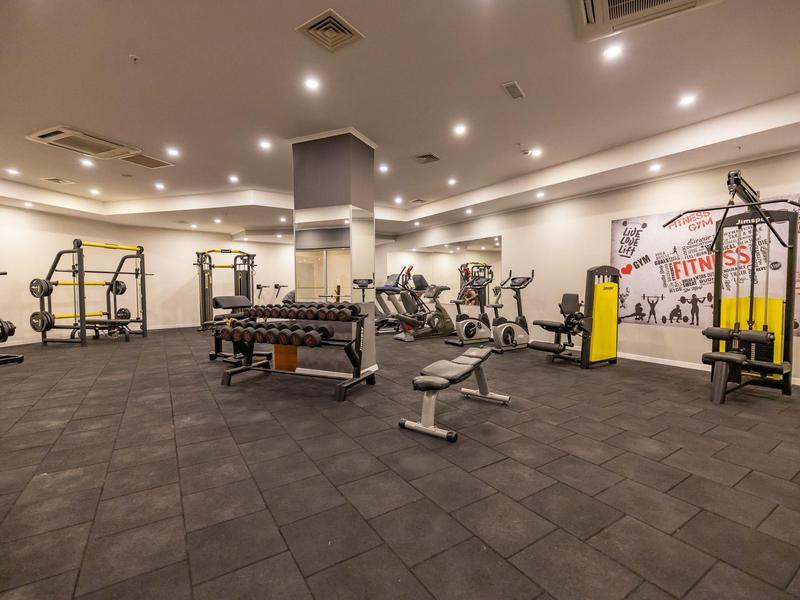 Spacious hotel gym with various exercise machines and warm lighting.