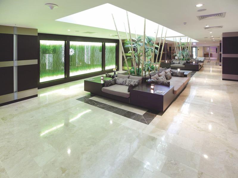 Heller, moderner Innenraum mit großem Aquarium, Pflanzen und glänzendem Marmorboden.