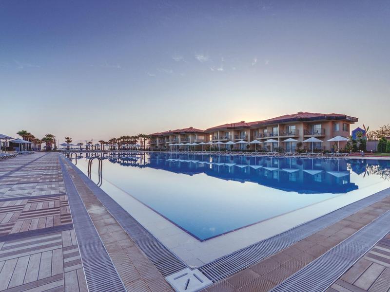 Großer Outdoor-Pool mit klarem Wasser neben modernen Gebäuden bei klarem Himmel am Abend.