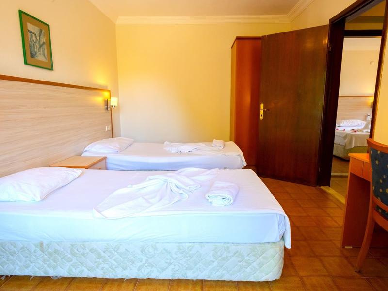 A hotel room with two single beds, a chair, and a desk next to an open door.