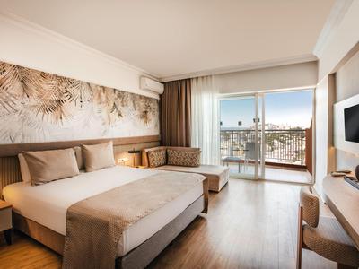 Chambre d'hôtel lumineuse avec lit double, balcon et décoration moderne.