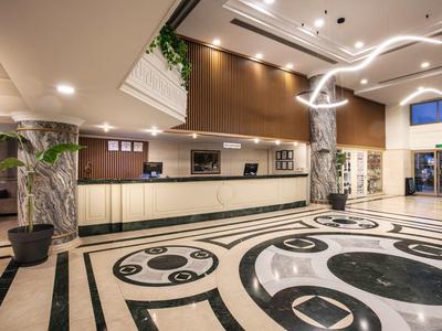 Moderní hotelová hala s křivkovou mozaikovou podlahou a recepcí.