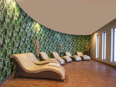 Stylová relaxační místnost s zakřivenými lehátky a zelenou tapetou s listy