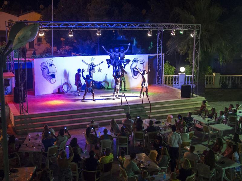 Večerní taneční představení na osvětleném venkovním pódiu před publikem.