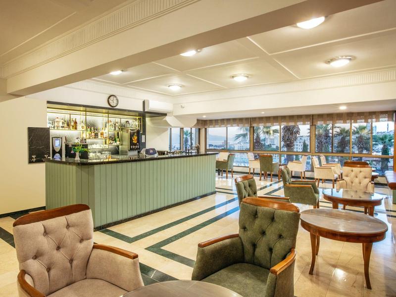 Světlá hotelová lobby s pohodlnými křesly, stoly a barem v pozadí.