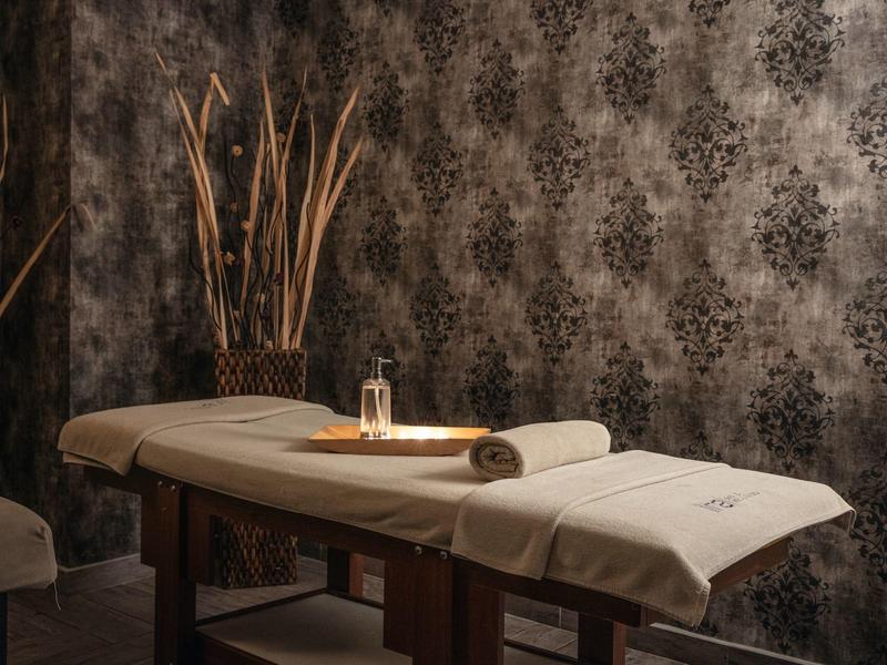 Pohodlná spa místnost s masážním stolem a tlumeným osvětlením.