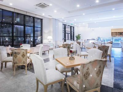 Licht, modern restaurant met witte muren, houten tafels en comfortabele stoelen met patroonstoffering.