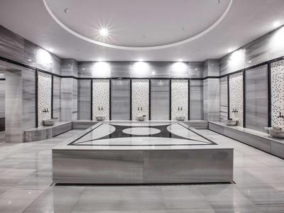 Modern Turks hamam met marmeren bassin en decoratieve wandpanelen.