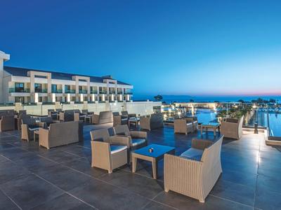 Modern buitenterras van hotel met zitplaatsen en zwembad bij zonsondergang.