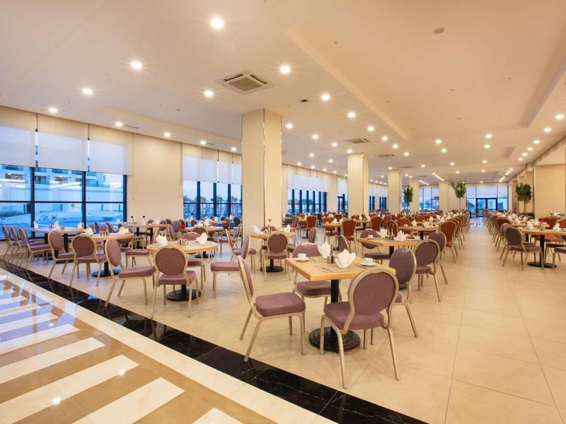 Grote moderne eetzaal met veel tafels en stoelen in een hotel.