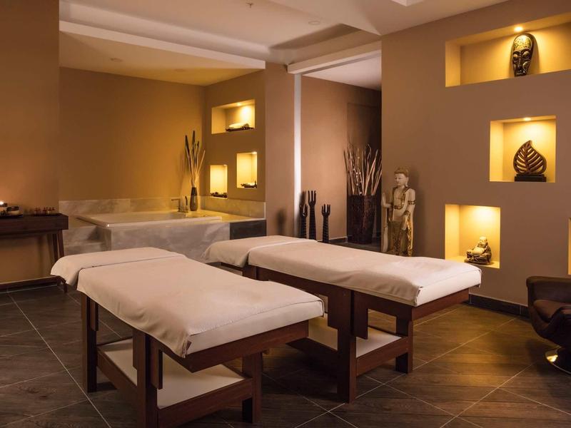 Rustige spa-ruimte met twee massagetafels, warme verlichting en decoratieve elementen.