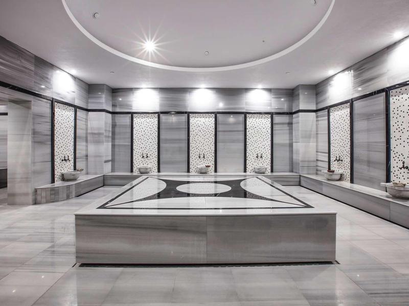 Modern Turks hamam met marmeren bassin en decoratieve wandpanelen.