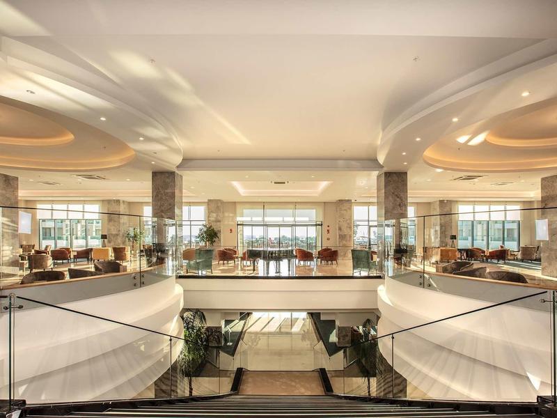 Ruime, elegante hotel lobby met gebogen trappen en veel natuurlijk licht.