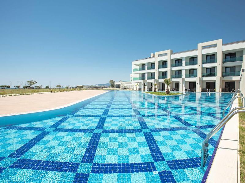 Moderne hotelzwembad met blauw gemêleerde tegels en uitzicht op een zandlandschap.