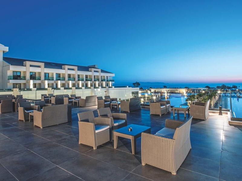 Modern buitenterras van hotel met zitplaatsen en zwembad bij zonsondergang.