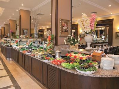 Buffet mit vielfältigen Salaten, Gemüse, Obst und dekorativen Blumenarrangements in hellem Raum.
